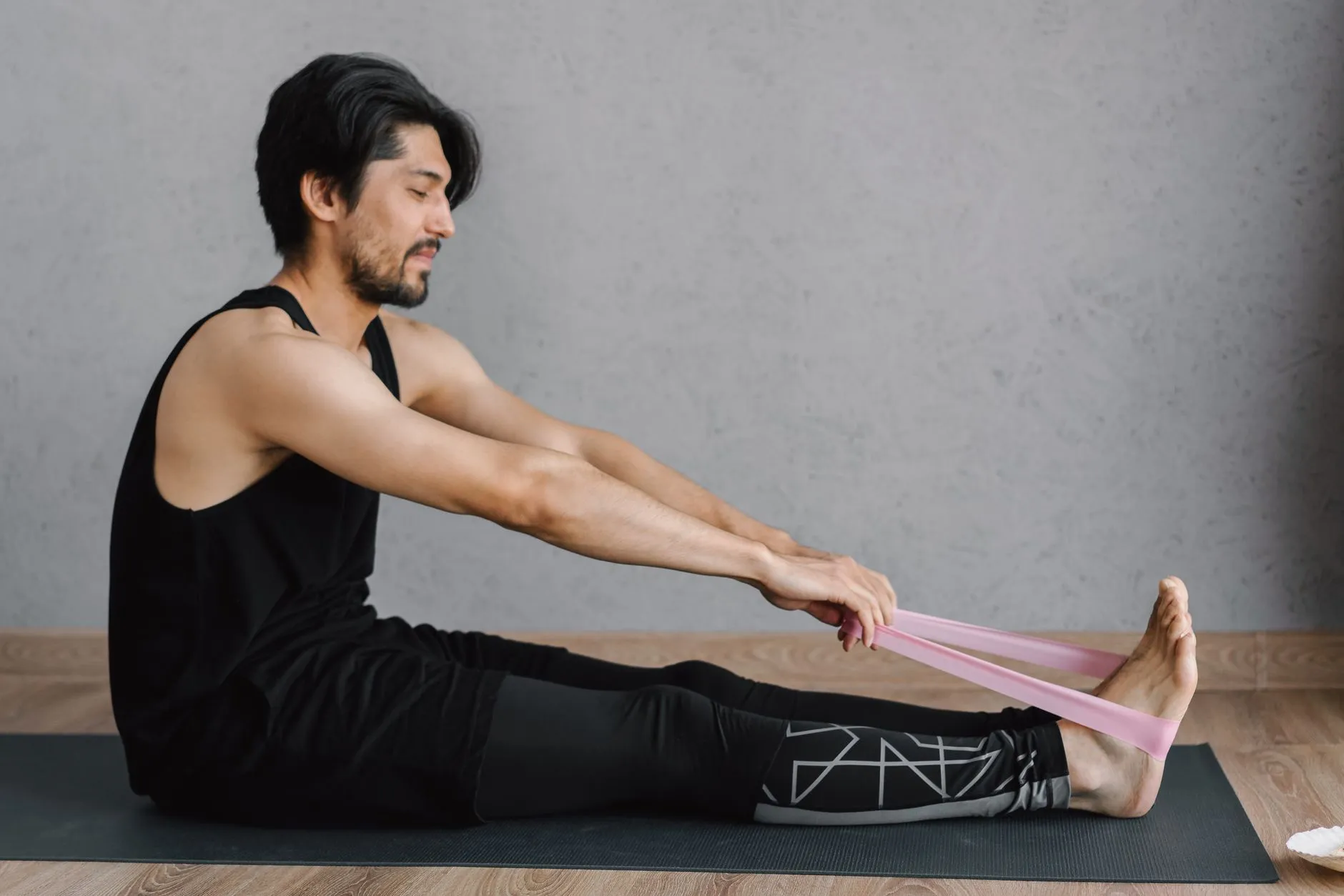 A man stretching with a resistance band on a mat