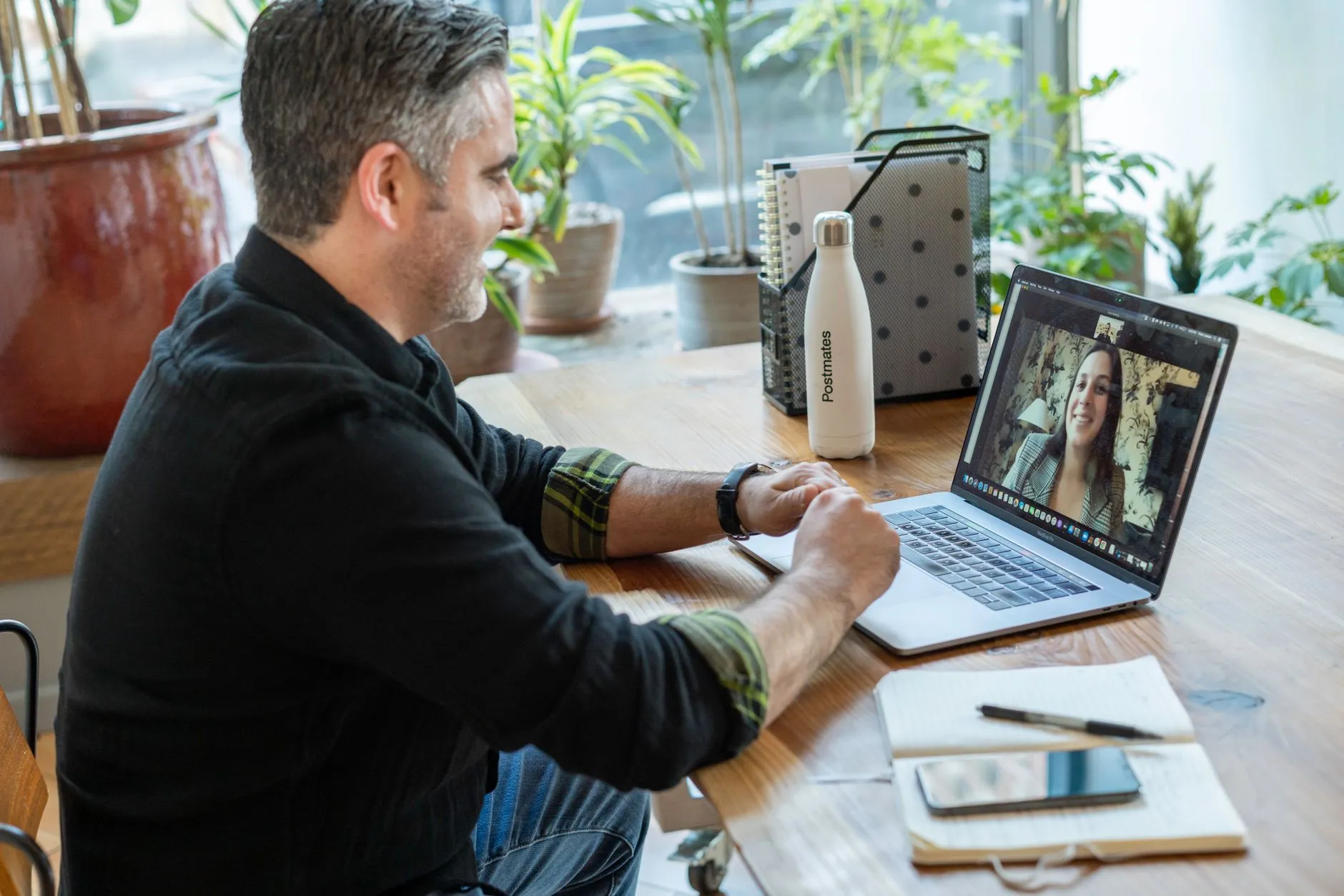 A man on a video call at his laptop, taking notes