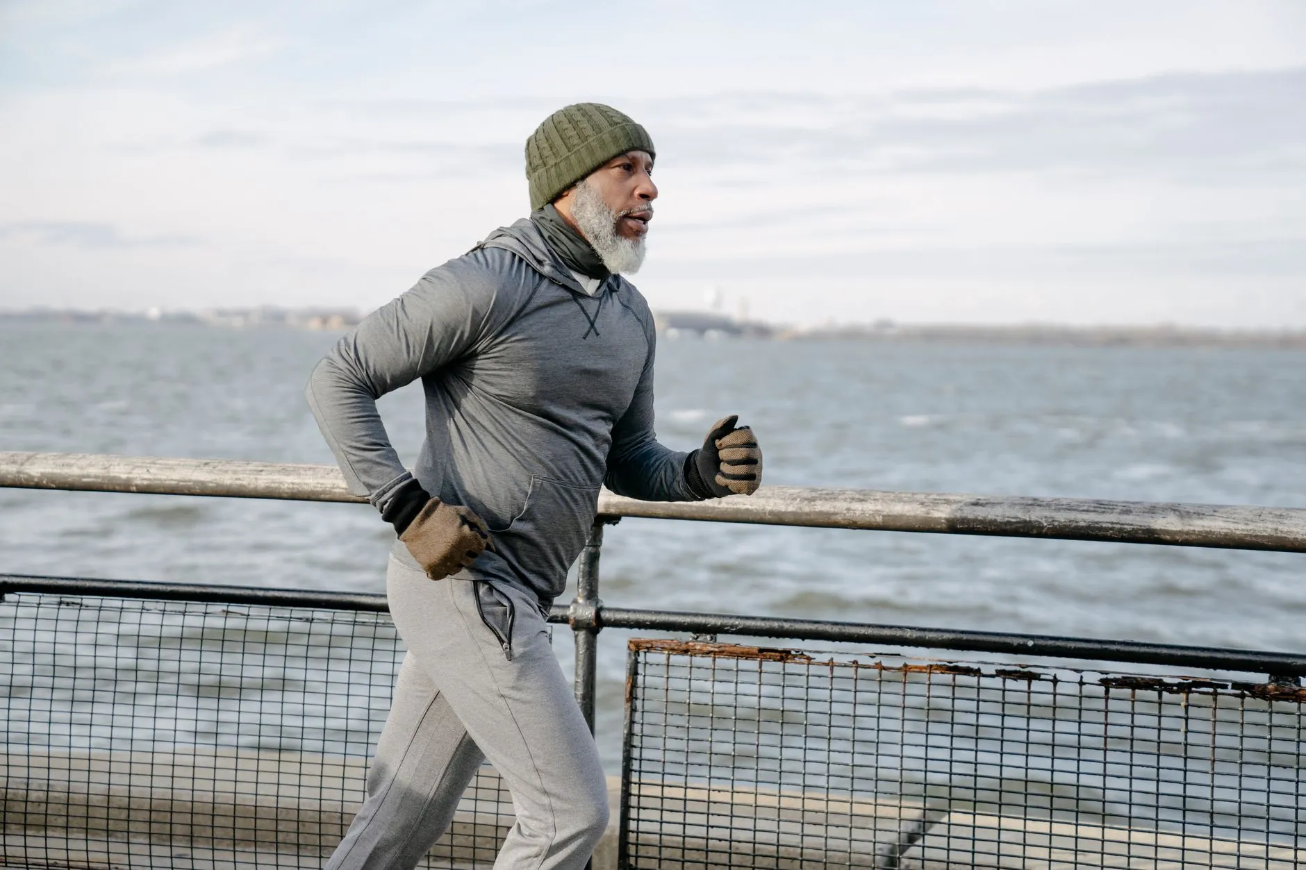 A grey-bearded man on an easy run along the water