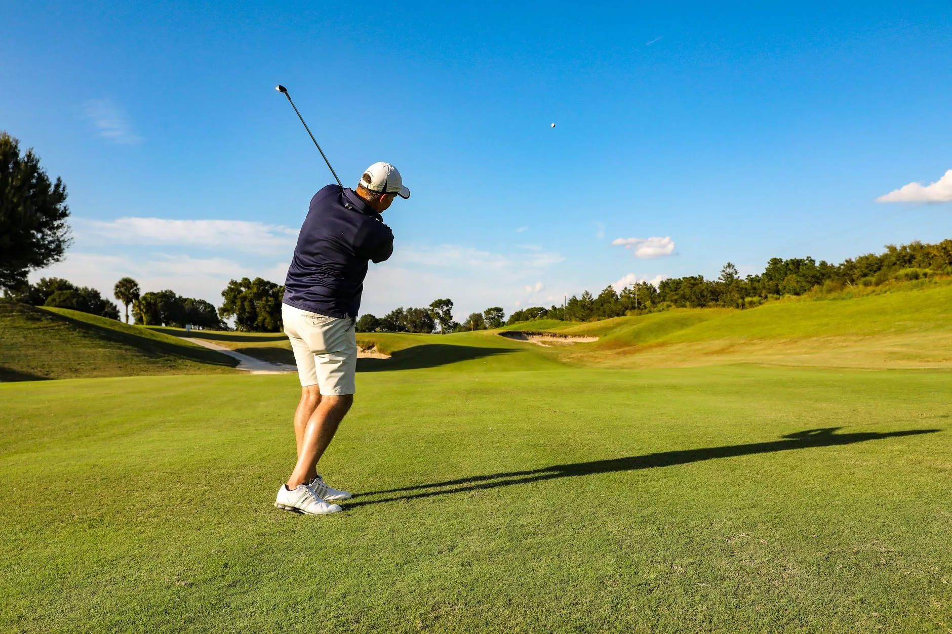 A golfer mid-swing on a sunny course