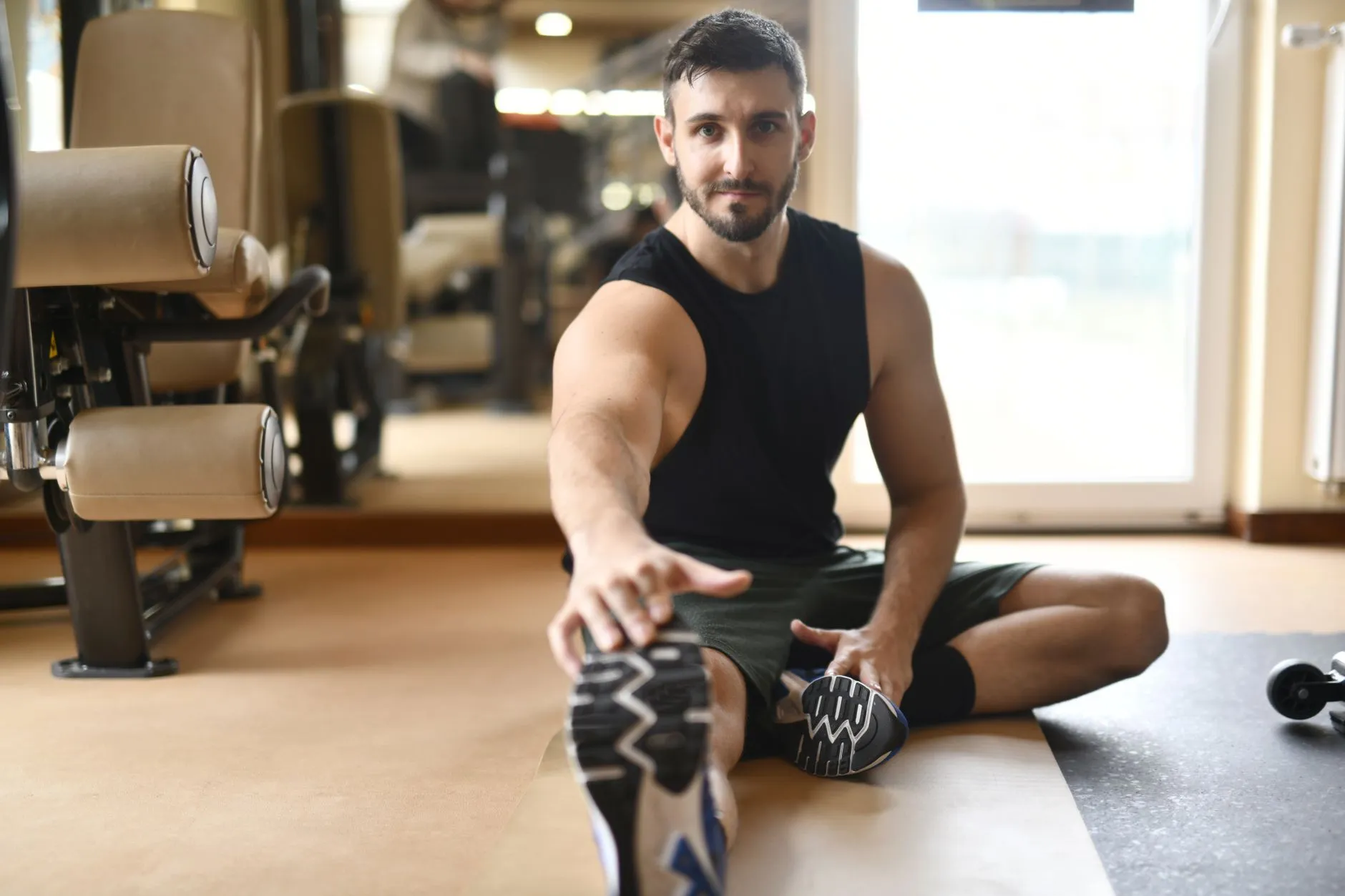 A man stretching his leg on the gym floor